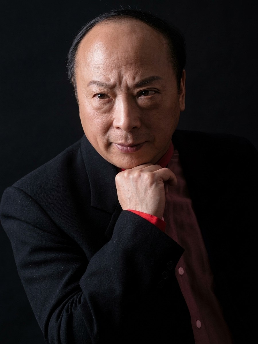 傅腾龙肖像,深色西装,手托下颌,暗底
